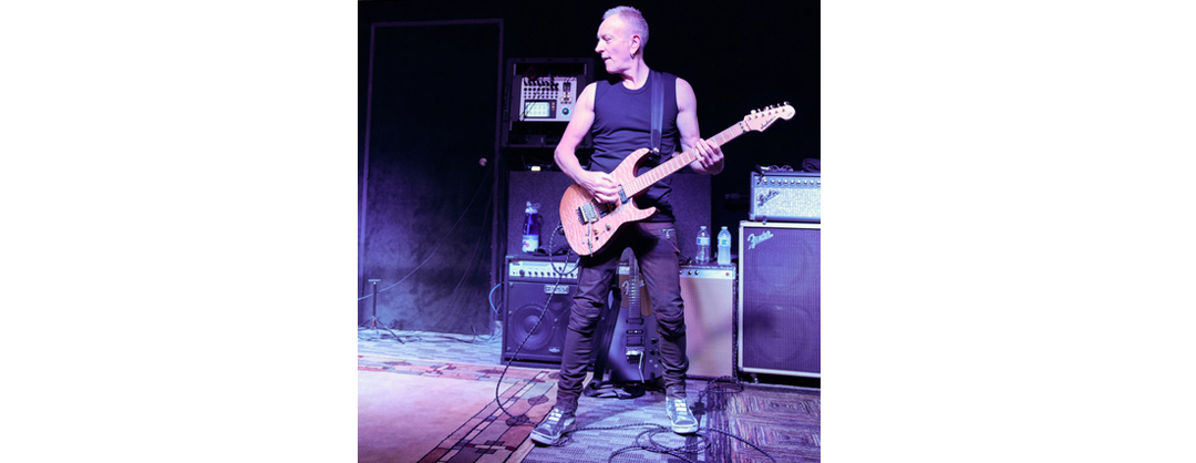 Phil Collen performing with a guitar
