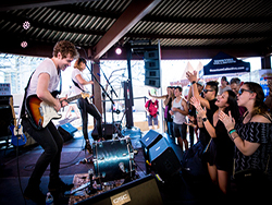 Band performing, with QSC speakers and subwoofers, on stage at Southwest Invasion