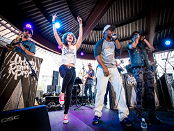 Band performing, with QSC speakers and subwoofers, on stage at Southwest Invasion