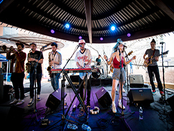 Band performing, with QSC speakers and subwoofers, on stage at Southwest Invasion