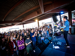 Band performing, with QSC speakers and subwoofers, on stage at Southwest Invasion