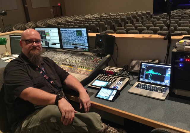 Eugene “Geno” Mulcahy sitting in front of production AV equipment including a QSC TouchMix-16