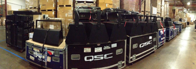 QSC Cinema speakers stacked on top of travel cases